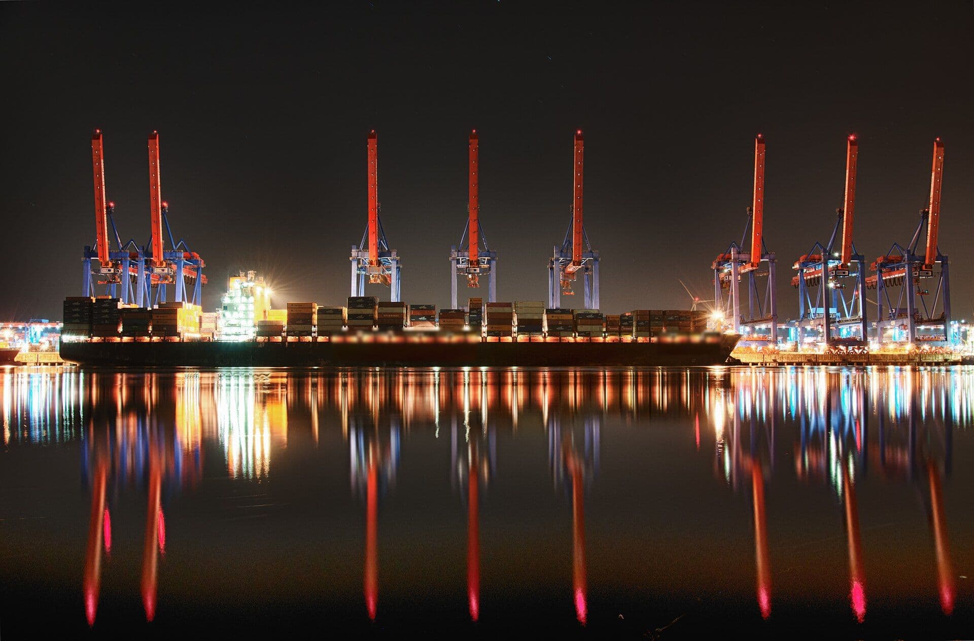 Container cranes working a vessel at an illuminated night terminal