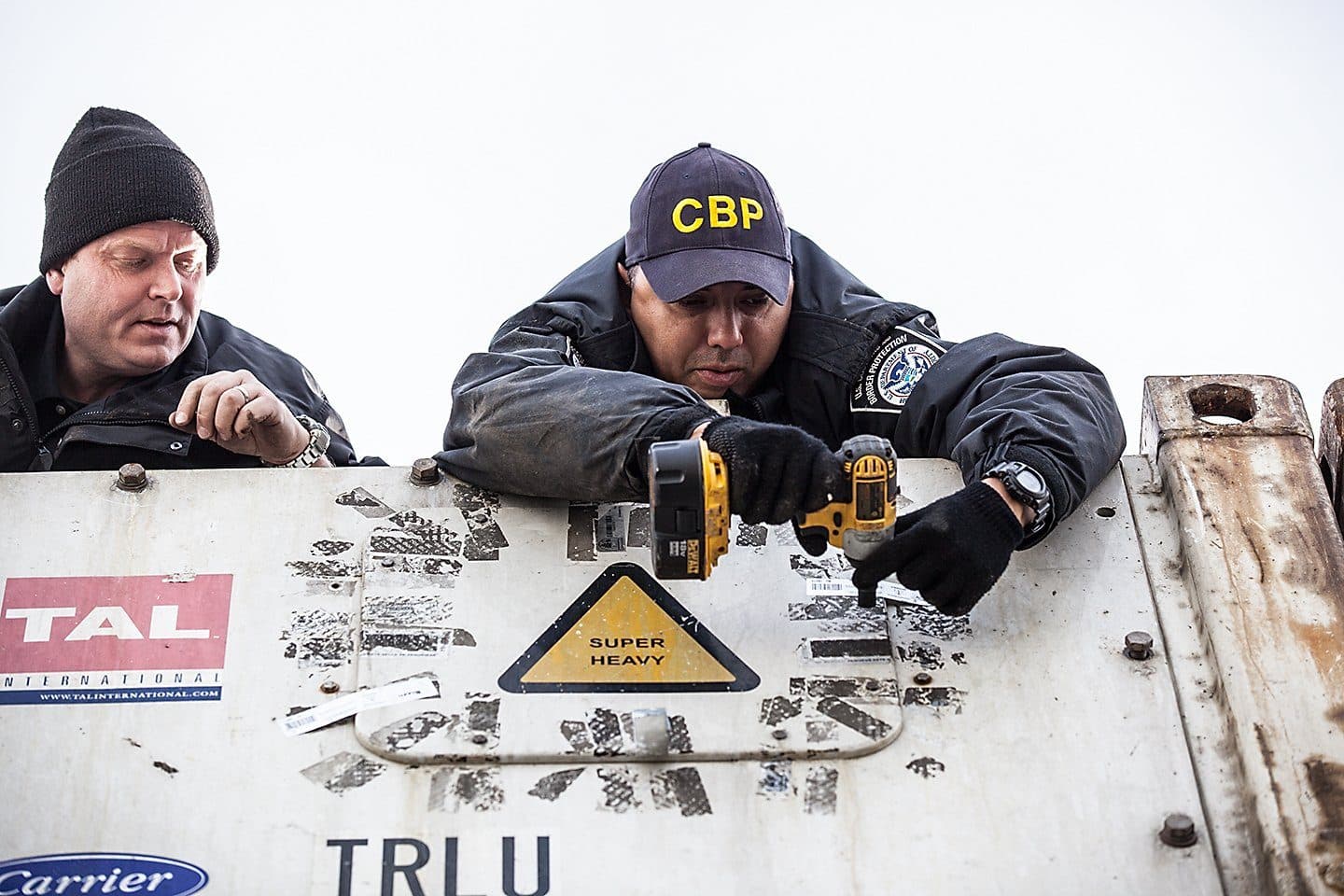 Customs officers inspecting a shipping container seal