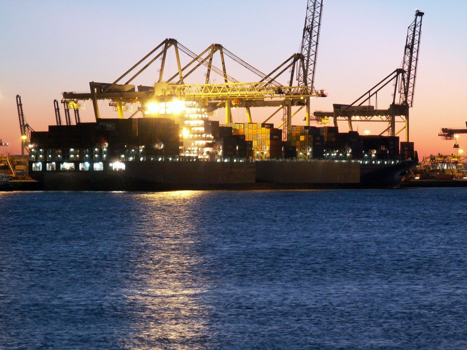 Container vessel being worked by quay cranes at dusk